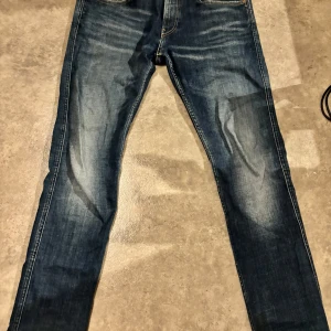 Blå jeans från Replay - Snygga blå jeans från Replay med klassisk femficksdesign och läderpatch baktill. Jeansen har en modern passform och är perfekta för en avslappnad stil. De är i bra skick! De sitter mindre i midjan men långs desamma! Ca 32 i midjan kanske 31 skulle jag tippa på!