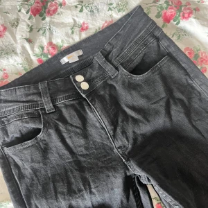 Svarta jeansbyxor från Gina Tricot - Säljer ett par svarta jeansbyxor från Gina Tricot i storlek 170 (tall). Byxorna har utsvängda ben, klassiska fem fickor och dubbla knappar i midjan. Perfekta för dig som gillar en enkel och stilren look. Använda en gång men de var alldeles för långa, därför något slitna i kanten längst ner.