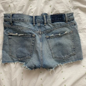 Blå jeansshorts med slitningar och fransar - Säljer ett par blå jeansshorts från Zara med råa fransade kanter.