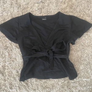 Svart Gina topp - Säljer denna så fina tie toppen från Gina som är helt slutsåld!! Den är i xs och använd en gång