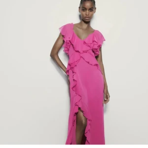 Rosa klänning med volanger - Säljer en fantastisk rosa klänning med volanger och slits. Klänningen har en v-ringad design och är perfekt för sommaren. I jätte bra skick!