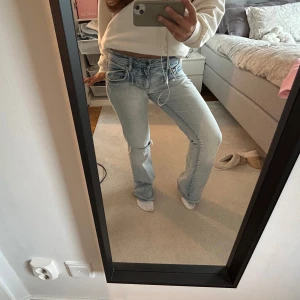 Ljusblå bootcut jeans med slitning - Säljer ett par ljusblå jeans med bootcut-modell och slitning vid knät. Har gjort hålet själv och det har även råkat spricka men har sytt igen det (syns närmare på sista bilden). Annars knga defekter, dom är sparsamt använda! Skriv gärna om mått eller andra frågor!🩷🩷