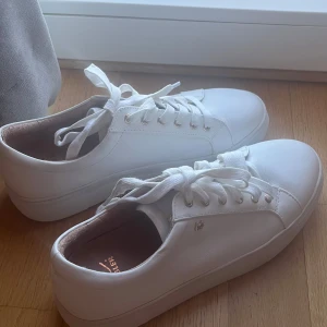 Vita sneakers från K Cobler - Snygga vita sneakers från K Cobler med snörning och rund tå. Perfekta för en stilren look och passar till många olika outfits. Skorna har en klassisk design med en bekväm passform.