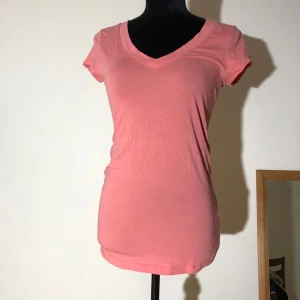 Rosa t-shirt - Rosa t-shirt från h&m med stor v-ringning fram. Längd ca 70cm.