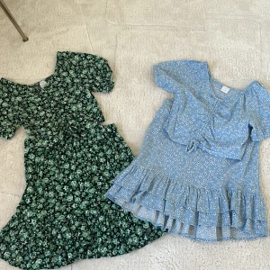 Blommiga set i grönt och blått - Två söta set med topp och kjol. Det gröna setet har ett blommigt mönster med volanger och knytning på toppen. Det blå setet har små blommor, volanger och en knytning framtill. Perfekt för en somrig look!