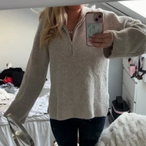 Beige stickad tröja med dragkedja - Mysig beige stickad tröja med dragkedja framtill. Perfekt för kyligare dagar med sin avslappnade passform och långa ärmar. En stilren och bekväm tröja för alla tillfällen.