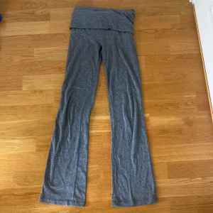 Grå yogapants från Gina Tricot - Grå yogapants från Gina Tricot med låg midja och utsvängda ben. Byxorna är gjorda i mjukt och stretchigt material, perfekta för en chill och avslappnad stil. Passar dig som gillar bekväma och trendiga plagg.