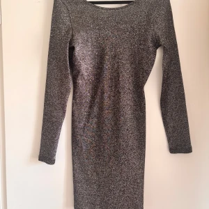 Glittrig silverklänning från Hm - Snygg långärmad klänning i glittrigt silver. Tight passform med rund halsringning fram och djupare urringning bak. 