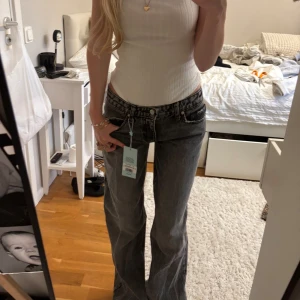 Grå wide jeans från Revice Los Angeles - Säljer ett par gråa jeans från Revice Los Angeles med låg midja och vida  ben. Helt nya och prislappen är kvar. Säljer då dom tyvärr är för långa för mig. Storlek 23 och jag är 160. Originalpris ca 1000kr. 