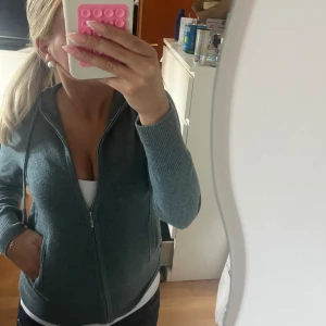Tröja från Soft Goat - Mysig grå hoodie från Soft Goat i lyxig kashmir. Jackan har dragkedja framtill, huva med snörning och ribbade muddar. Perfekt för dig som vill ha en stilren och bekväm look med premiumkänsla. Snygg att bära både öppen och stängd.