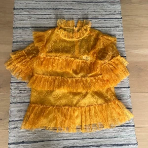 Gul spetsblus med volanger By Malina - Superfin gul/orange blus från By Malina i spets med volanger över hela toppen. Perfekt för dig som vill sticka ut med färg och detaljer.💕