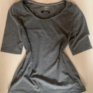 Mörkgrå topp från Gina Tricot - mörkgrå topp från Gina Tricot med rund halsringning och halvlånga ärmar. Säljer för att den tyvärr är för stor för mig.