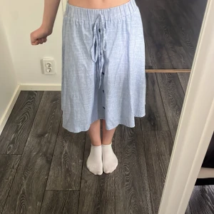 Blåvit randig midikjol med knyt - Säljer en blåvit randig kjol med knyt i midjan och knappar framtill. Jag ser ingen storlek men skulle tro mellan XS och S. Jag är 164cm så utgå från det🤗 