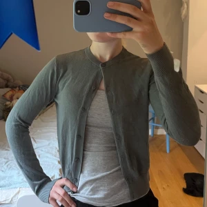 Grå kofta från H&M XS - En enkel och stilren grå kofta från H&M i storlek XS. Koftan har rund halsringning, långa ärmar och knäppning framtill med små knappar. Perfekt att slänga över en t-shirt för en chill look.