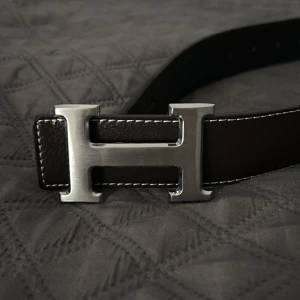  Bälte med svart skärp H-spänne - Snyggt svart skärp  med ikoniskt H-spänne i silverfärgad metall. . Perfekt accessoar för att lyfta din outfit med en lyxig touch.