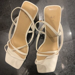 Vita klackar från H&M - Snygga vita sandaler från H&M med fyrkantig tå, tunna remmar och blockklack. Sköna! Lite smink på remmen som går att få bort 