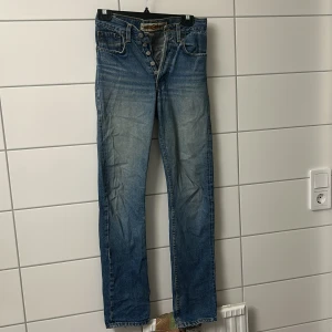  blå jeans straight fit - Klassiska blåa  jeans med raka ben och knäppning framtill. Snyggt slitna detaljer och autentisk vintagekänsla. Perfekta för dig som gillar tidlös denimstil.