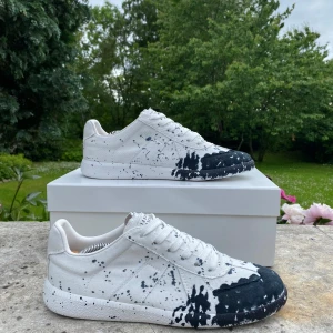Maison Margiela GATS(kvitto finns) - Unika vita GATS med svart färgstänksmönster över tå och sidor. Klassisk låg modell med snörning och platt sula. Perfekta för dig som vill sticka ut med en kreativ och modern stil. Om du undrar något är det bara att fråga, svara så snabbt jag kan✅🙌