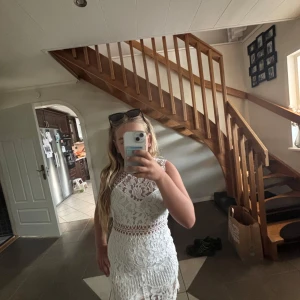 Vit spetsklänning med detaljer - Superfin vit spetsklänning med blommigt mönster och snygga genombrutna detaljer i midjan. Ärmlös modell med figurnära passform och rund halsringning. Perfekt för sommarens alla tillfällen och ger en romantisk vibe. Lappen är borta men det är en klänning för folk vid 10 årsålden. 