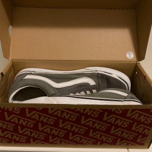 Vans Old Skool grå/vita sneakers - Klassiska Vans Old Skool sneakers i grått och vitt med vit sula och ikonisk sidorand. Ovandel i mocka och canvas, snörning framtill och rund tå. Perfekta för en avslappnad streetstil och passar till det mesta. Använde dom i bara  2 veckor efter som de blev för små. Det är bra skick en fläcka från glass på den vänstra skon. Pris kan diskuteras 