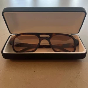 Bruna solglasögon Corlin Eyewear - Solglasögon från Corlin Eyewear med brunmelerad båge i klassisk fyrkantig form och bruna tonade glas. Kommer med originalfodral och tygpåse. Nypris 1200 
