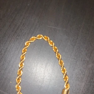 Guldfärgat tvinnat armband - Snyggt guldfärgat armband med tvinnad kedja som ger en cool och trendig look. Perfekt för att lyfta vilken outfit som helst med lite extra bling. Passar dig som gillar statement-smycken och vill sticka ut. Skriv för mer information 