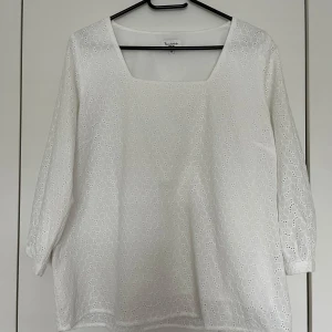 Vit blus, Bondelid, storlek M - Vit blus med fyrkantig halsringning och 3/4-ärmar från Bondelid i storlek M. Blusen har ett broderat hålmönster över hela ytan och är fodrad. 100% bomull.  Nyskick.   Mått: Längd ca 60 cm Byst ca 50 cm Midja ca 50 cm Ärmlängd mätt från axeln ca 46 cm Axel till axel ca 41 cm  Nypris 599kr.
