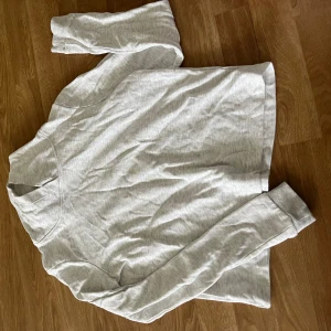 Ljusgrå långärmad sweatshirt - En stilren ljusgrå långärmad sweatshirt med rund hals och ribbade muddar vid ärmsluten. Perfekt för en chill och avslappnad look. Mjuk och skön, passar till jeans eller mjukisbyxor.