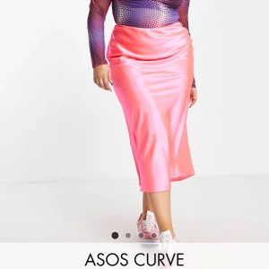 Rosa satinkjol från ASOS Curve - Snygg långkjol i glansigt rosa satin från ASOS Curve. Kjolen har en rak passform och resår i midjan för extra komfort. Oanvänd men prislapp saknas. Köpt för ca 300kr