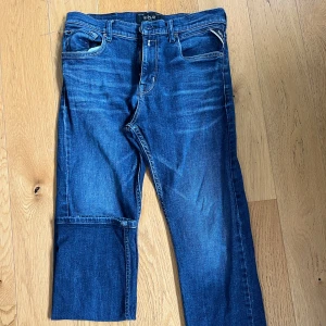 Blå jeans från Replay straight fit - Säljer ett par klassiska blå jeans från Replay med raka ben och snygga detaljer på bakfickorna. De är mörkare än vad de ser ut. Barnmodell och passar en som 12-14 år gammal. 