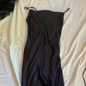 Svart långklänning med smala axelband - En stilren svart långklänning med smala axelband och slits nedtill. Den är jätte fin och sitter bra
