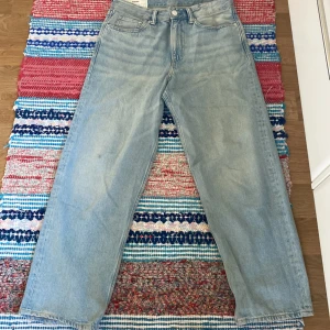 Ljusblå loose fit jeans från H&M - Ljusblå jeans från H&M i loose fit-modell med raka ben och klassisk femficksdesign. Jeansen har hög midja och är tillverkade i bomull. Perfekta för en avslappnad och trendig stil.