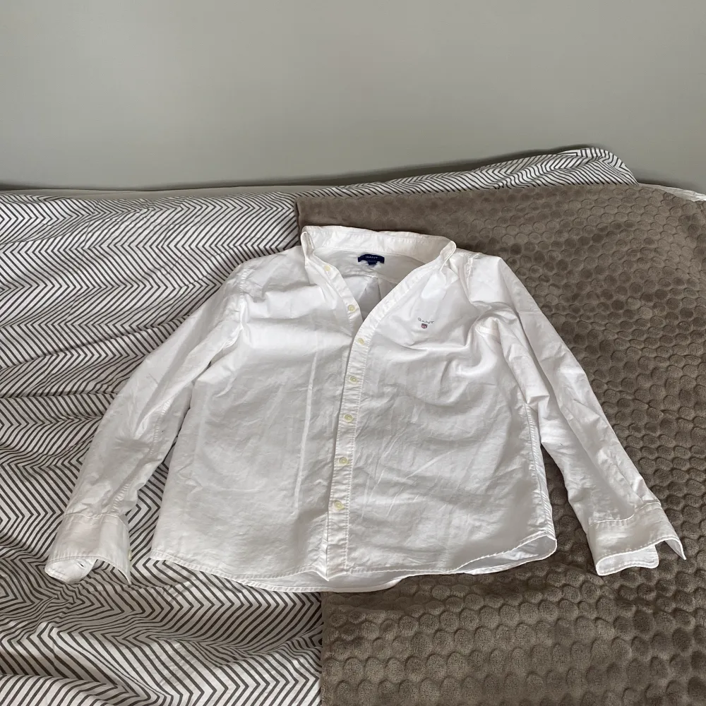 Säljer en klassisk vit skjorta från GANT. Skjortan har långa ärmar och knappar framtill. Perfekt för en stilren look. Passar ungdomar i åldern 13-14 år.. Paidat.