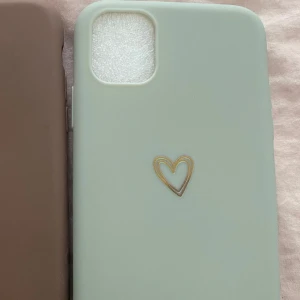 Mobilskal med hjärtdetalj från Shein - Snyggt silikon mobilskal från Shein i en mjuk grön färg med en stilren hjärtdetalj i guld. Passar iPhone 11  helt oanvänd 
