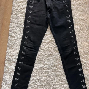 Svarta skinny jeans med nitar från H&M - Snygga svarta skinny jeans från H&M med coola nitar längs benen. Perfekta för att ge din outfit en edgy touch. De har en klassisk femficksdesign och är tillverkade i ett stretchigt material för bästa komfort. Stl 30/32