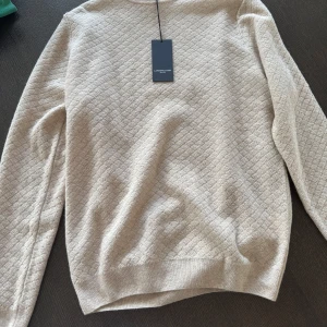 Beige stickad tröja från Lawrence Grey - Detta är en varm stickad tröja som har ett liggande diamantmönster, Prislapp finns kvar på tröjan och den har inte varit använd någongång.