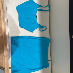 Turkos tvådelad klänning, aldrig använt - Snygg turkos tvådelad klänning med en ärmlös topp och en matchande kjol. Perfekt för sommarens varma dagar. Toppen har smala axelband och kjolen är kort och figurnära.