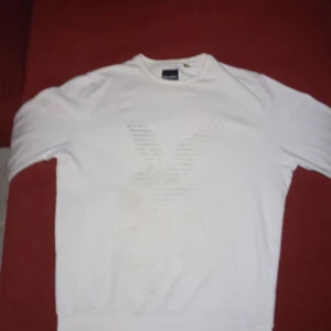 Vit tröja från Lyle & Scott - Säljer en stilren vit tröja från Lyle & Scott. Tröjan är tillverkad i 100% bomull och har en klassisk passform med långa ärmar. Perfekt för en avslappnad look. Är lite smutsig bakom men det går bort i tvätten väldigt lätt.
