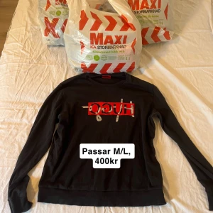 Svart tröja från Hugo boss - Snygg svart tröja från Hugo med ett rött och vitt tryck på framsidan. Tröjan har långa ärmar och en klassisk rund halsringning. Perfekt för en stilren look. Typ helt ny nästan aldrig använd, säljer mycket annat på min profil också så kolla!