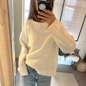 Vit stickad tröja - Säljer en mysig vit stickad tröja med lång ärm och rund hals. Perfekt för kyligare dagar och lätt att matcha med jeans eller kjol. Tröjan har en avslappnad passform som ger en skön och bekväm känsla.