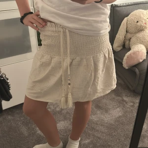 Vit kjol med smock och knytband - Vit beige kjol från Zara nyskick andvänd Max 2 gånger skkrriv för mer bilder