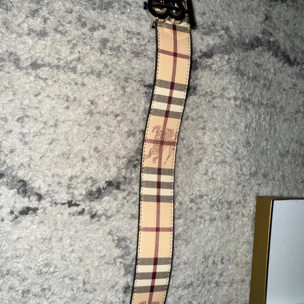 Snyggt bälte från Burberry med klassiskt rutigt mönster i beige, svart och röd. Bältet har ett stilrent spänne med Burberrys logotyp i silver. Perfekt för att ge en touch av lyx till din outfit. Pris kan diskuteras. Dm för mer frågor😇.. Asusteet.