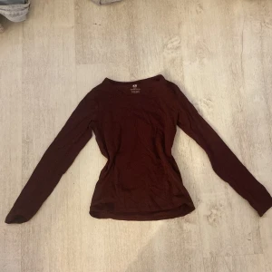 Vinröd långärmad topp från H&M - Säljer en vinröd långärmad topp från H&M i ekologisk bomull. Perfekt för en stilren och bekväm look. Toppen har en enkel design med rund halsringning.