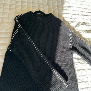 Svart stickad tröja från Gina Tricot - Säljer en svart stickad tröja från Gina Tricot med vita detaljer längs ärmarna. Tröjan har en klassisk rund hals och långa ärmar, perfekt för kyligare dagar. Ett stilrent plagg som passar till mycket. 🖤