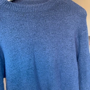 Blå stickad tröja från 157 - Säljer en mysig blå stickad tröja från 157. Tröjan har en rund halsringning och långa ärmar, perfekt för kyliga dagar. Den är enkel och stilren, vilket gör den lätt att matcha med olika outfits.