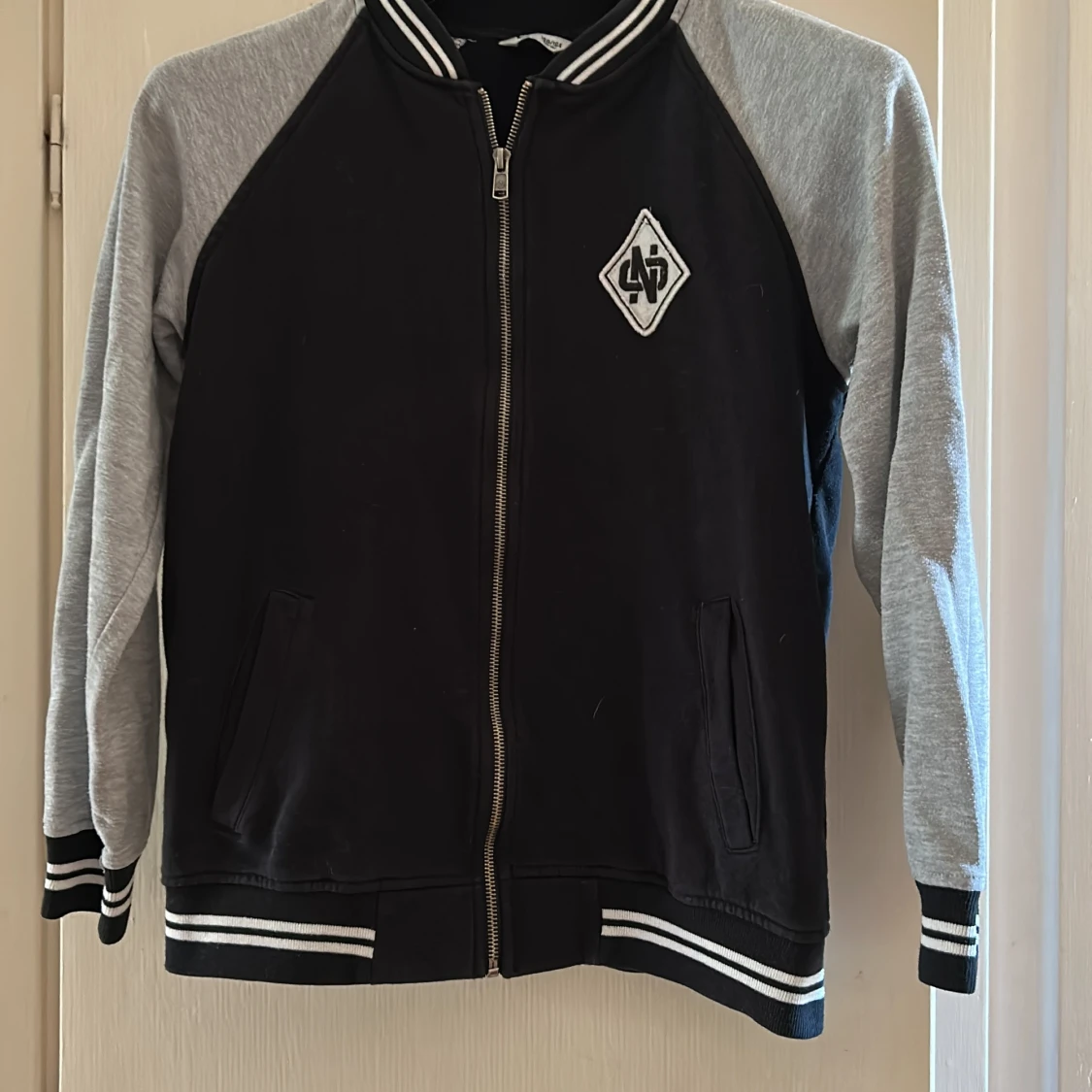Svart och grå bomberjacka med emblem