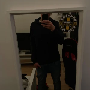 mörkblå hoodie från Les Deux - Säljer en mörkblå hoodie från Les Deux med diskret logga på bröstet. Tröjan har huva med snörning och långa ärmar. Perfekt för dig som gillar en clean och stilren look. Passar till jeans.