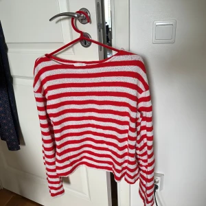 Rödvit randig stickad tröja H&M - Stickad tröja från H&M i rött och vitt med randigt mönster. Tröjan har lång ärm och rund halsringning.