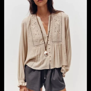 Beige broderad blus - Supersöt beige blus med broderade detaljer och hålmönster framtill. Blusen har v-ringning, klädda knappar och långa ärmar med volang vid ärmslut. Luftigt material och avslappnad passform. En helt ny blus från Zara och ordinarie pris är 379 men säjer för 200💓💓