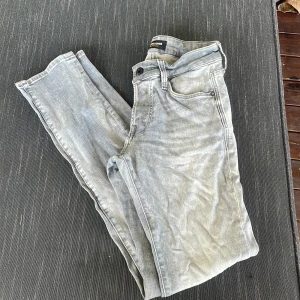 Ljusgrå skinny jeans Jack & Jones - Säljer ett par ljusgrå skinny jeans från Jack & Jones, modell Glenn. Jeansen har klassisk femficksdesign, snygga bakfickor och superstretch för extra bekvämlighet. Perfekta för dig som gillar en tight passform och stilren look.